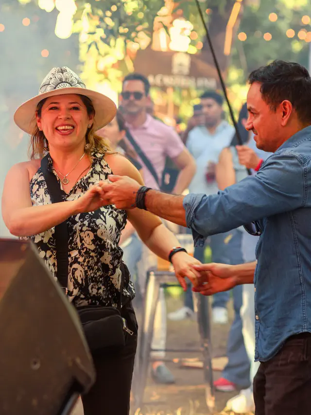 Dos personas bailando y riendo entre el público, de día