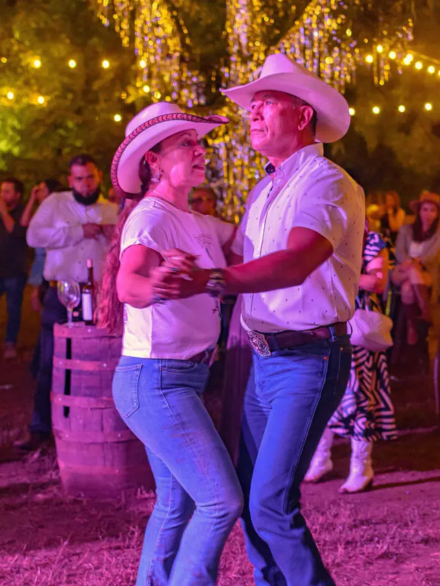 Una pareja bailando de noche bajo las series de foquitos