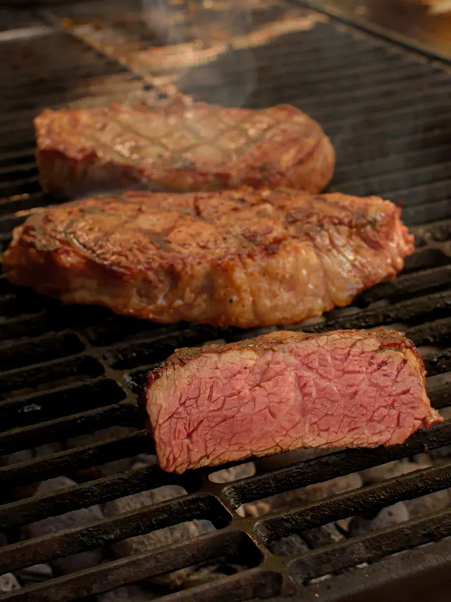 Cortes de carne sobre la parrilla; uno rebanado deja ver el término