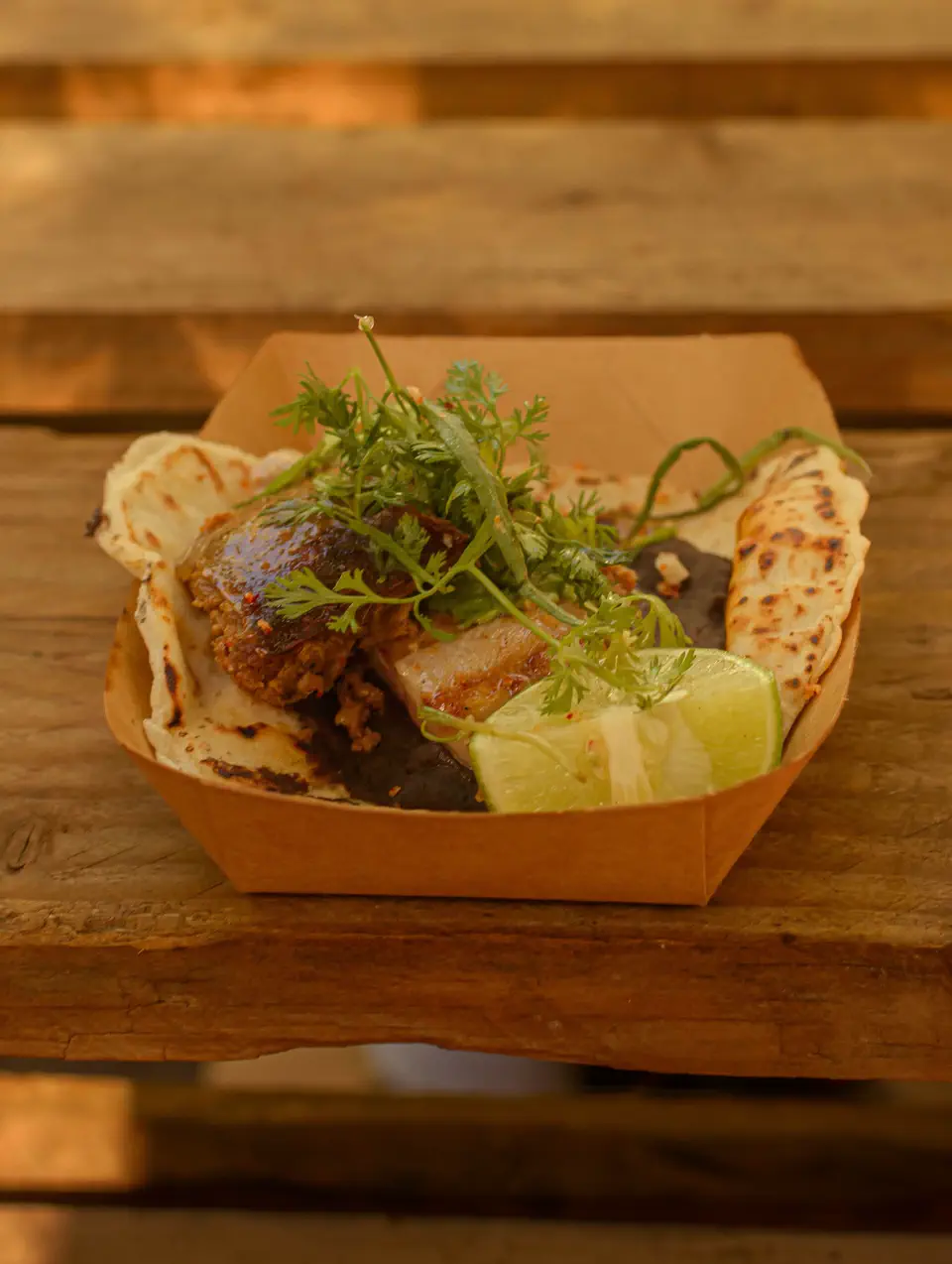 Charola de cartón con carne, cilantro, limón y tortillas recién hechas